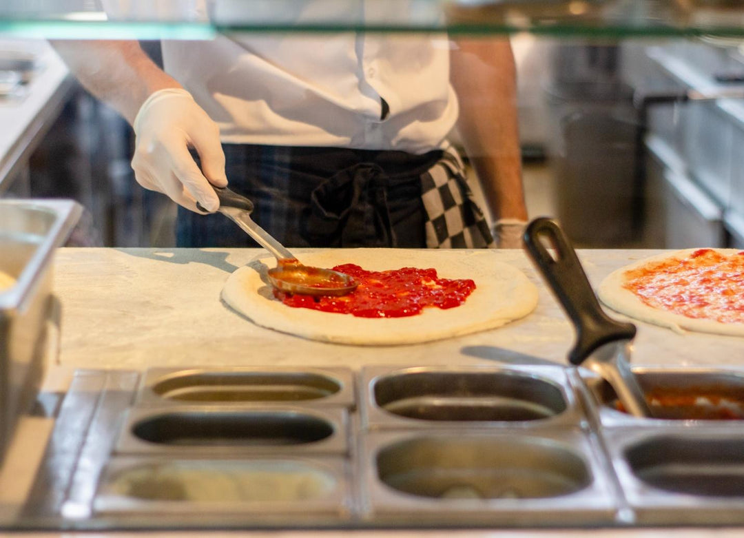 chef preparing pizza at kitchen table