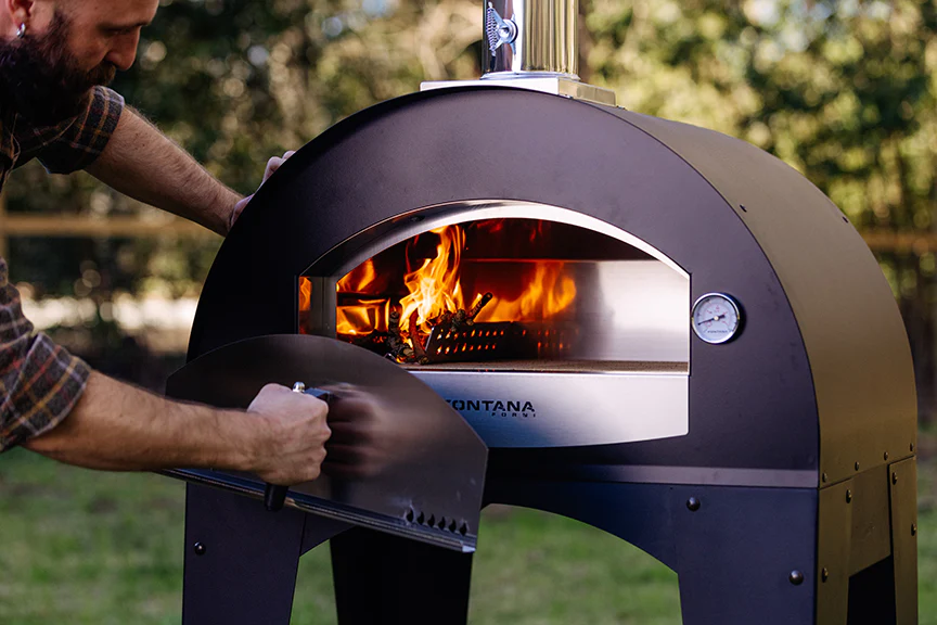 Man cooking in a Fontana Forni pizza oven while camping