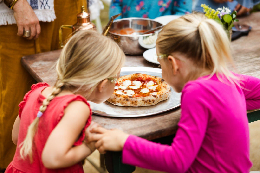 Young kids looking at a fresh made pizza