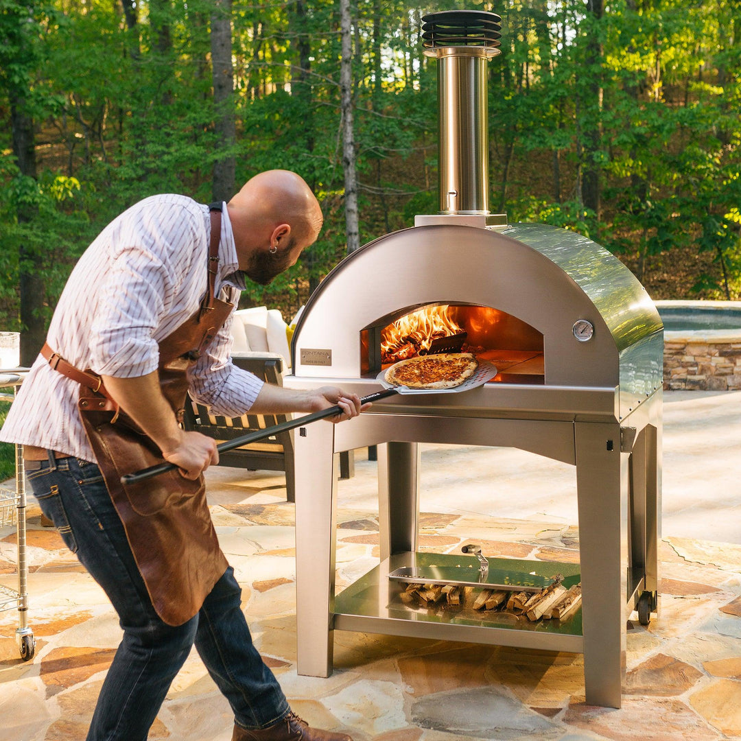 Young man check on pizza in wood fired oven
