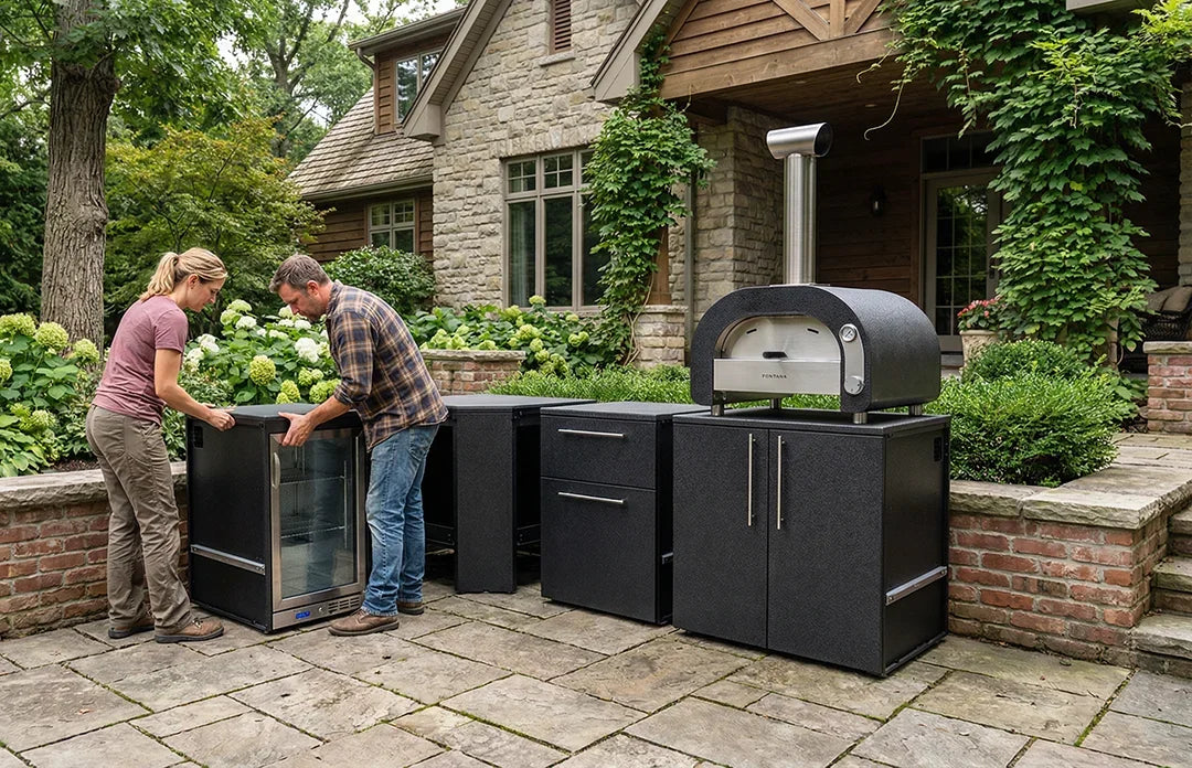 Two people interacting with Elysia outdoor kitchen cabinets and Maestro oven in a garden setting.