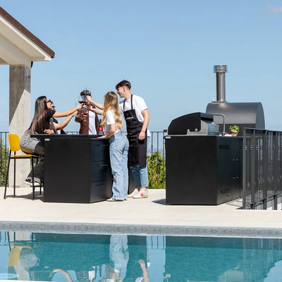 Group of 5 young adults clinking glasses over countertop of Elysia Outdoor Kitchen on patio by pool