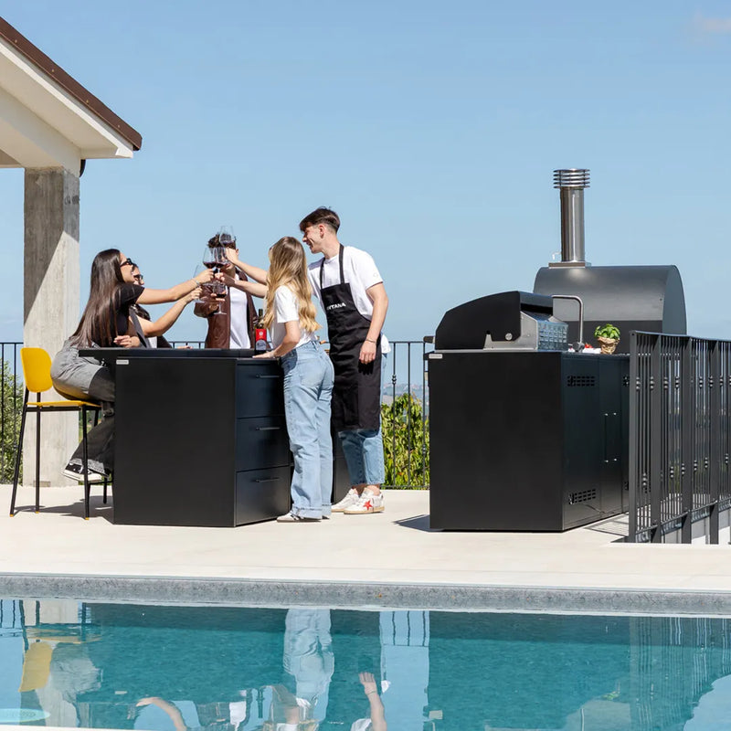 Group of 5 young adults clinking glasses over countertop of Elysia Outdoor Kitchen on patio by pool