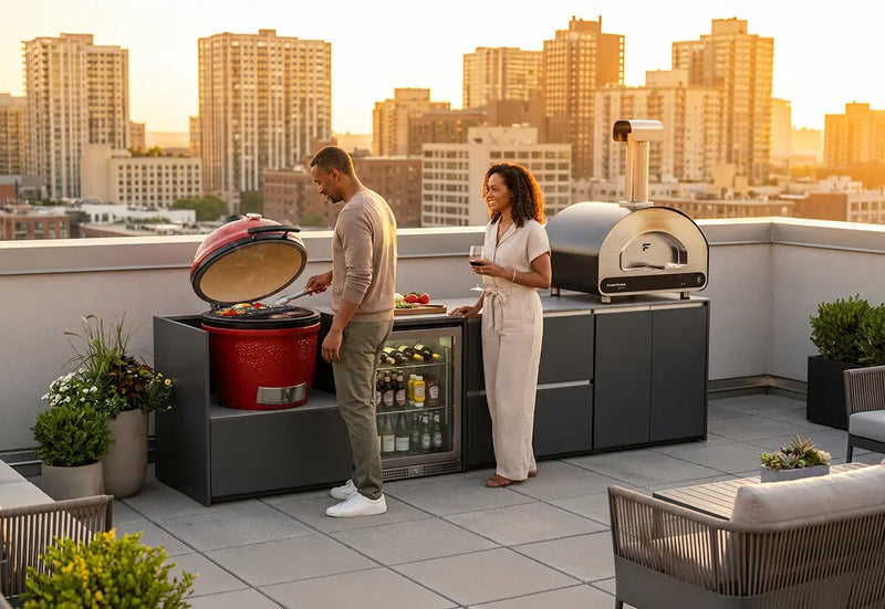 Two people enjoying a meal on a rooftop with Ember outdoor kitchen and cityscape in the background.